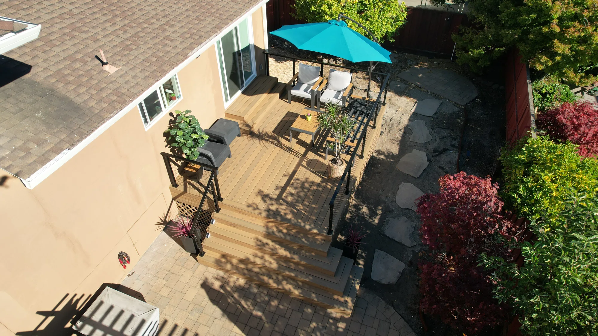 Drone view of deck steps, cable railing and flagstone stepping stones set in dark gravel landscaping.