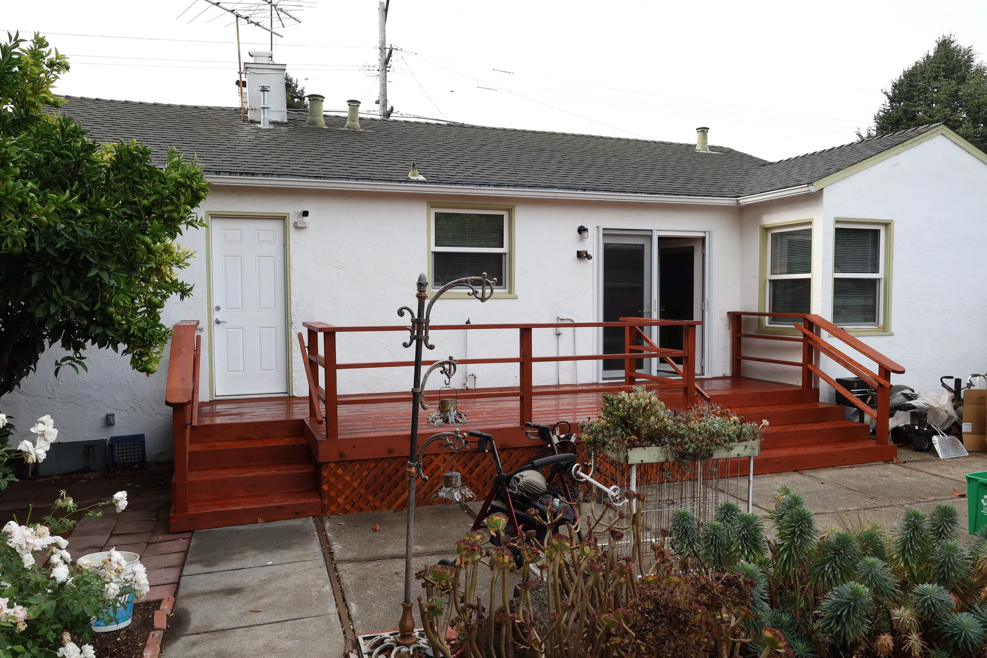 Freshly stained red wood deck with horizontal railings across the back of a single-story white stucco house.