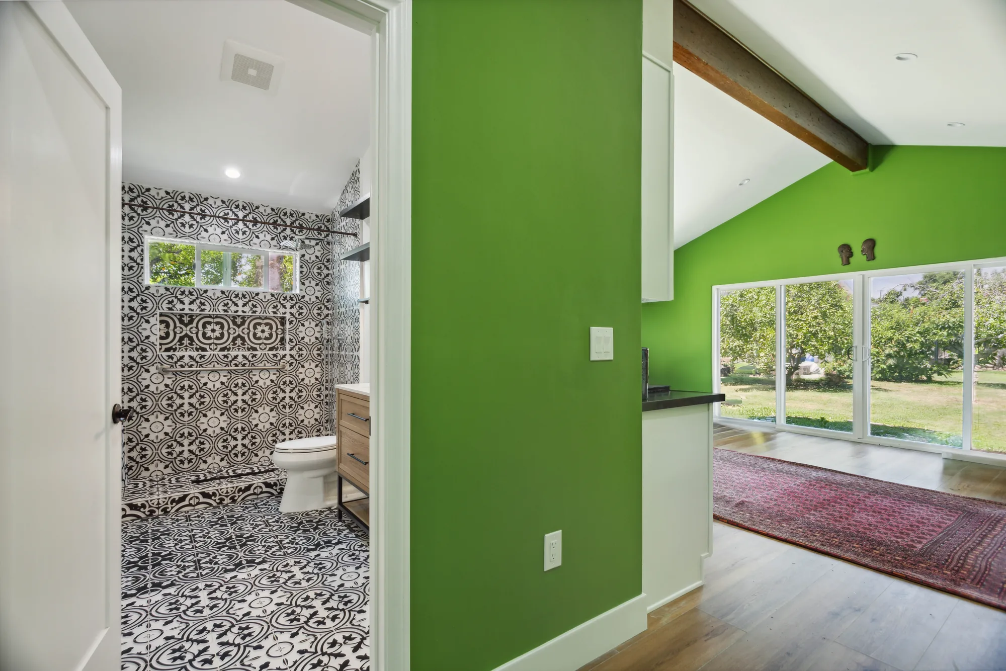 Doorway from the living area into a bathroom tiled floor to ceiling in black and white pattern.