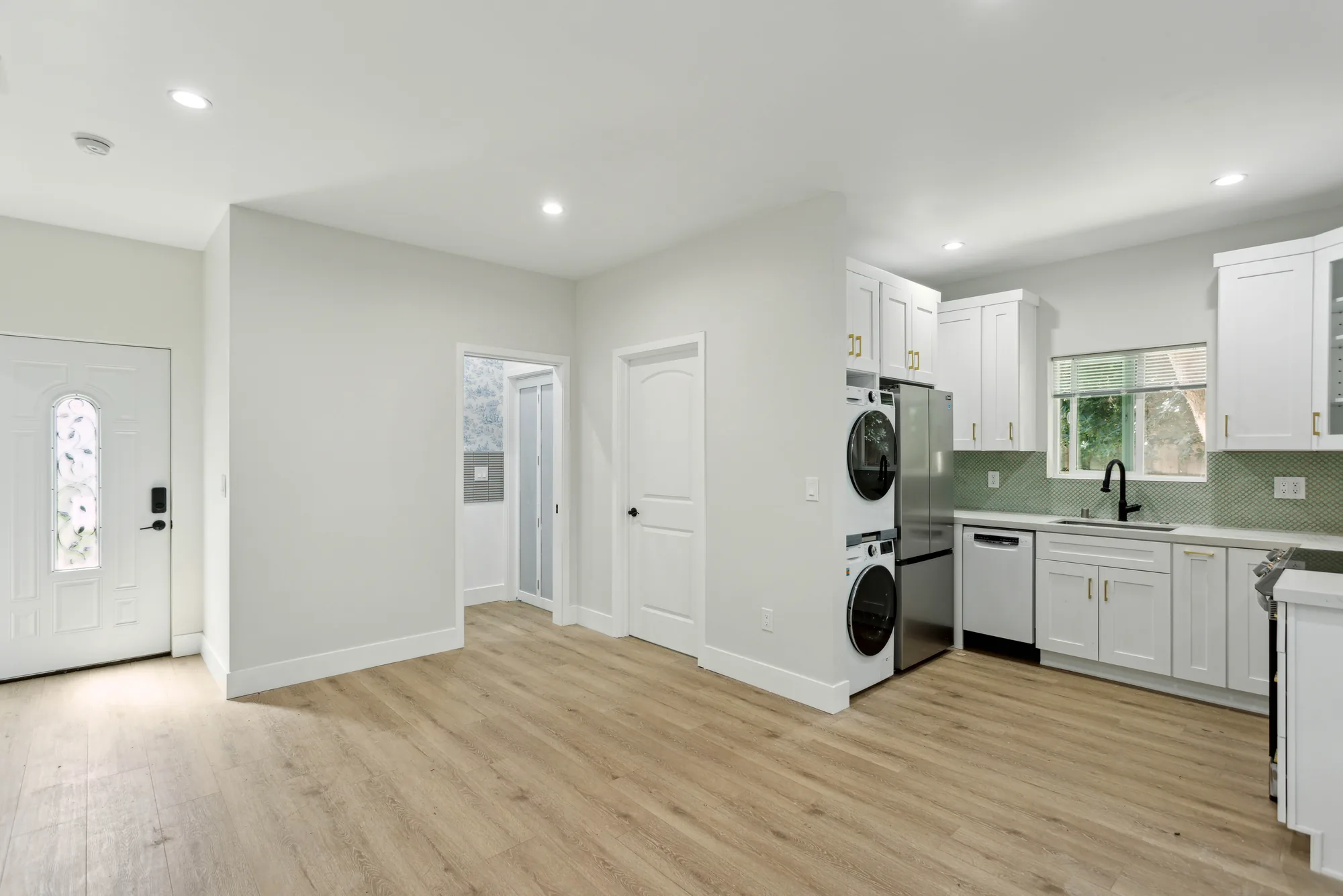 Wide interior view from the front door across the living area to the kitchen and laundry bay.