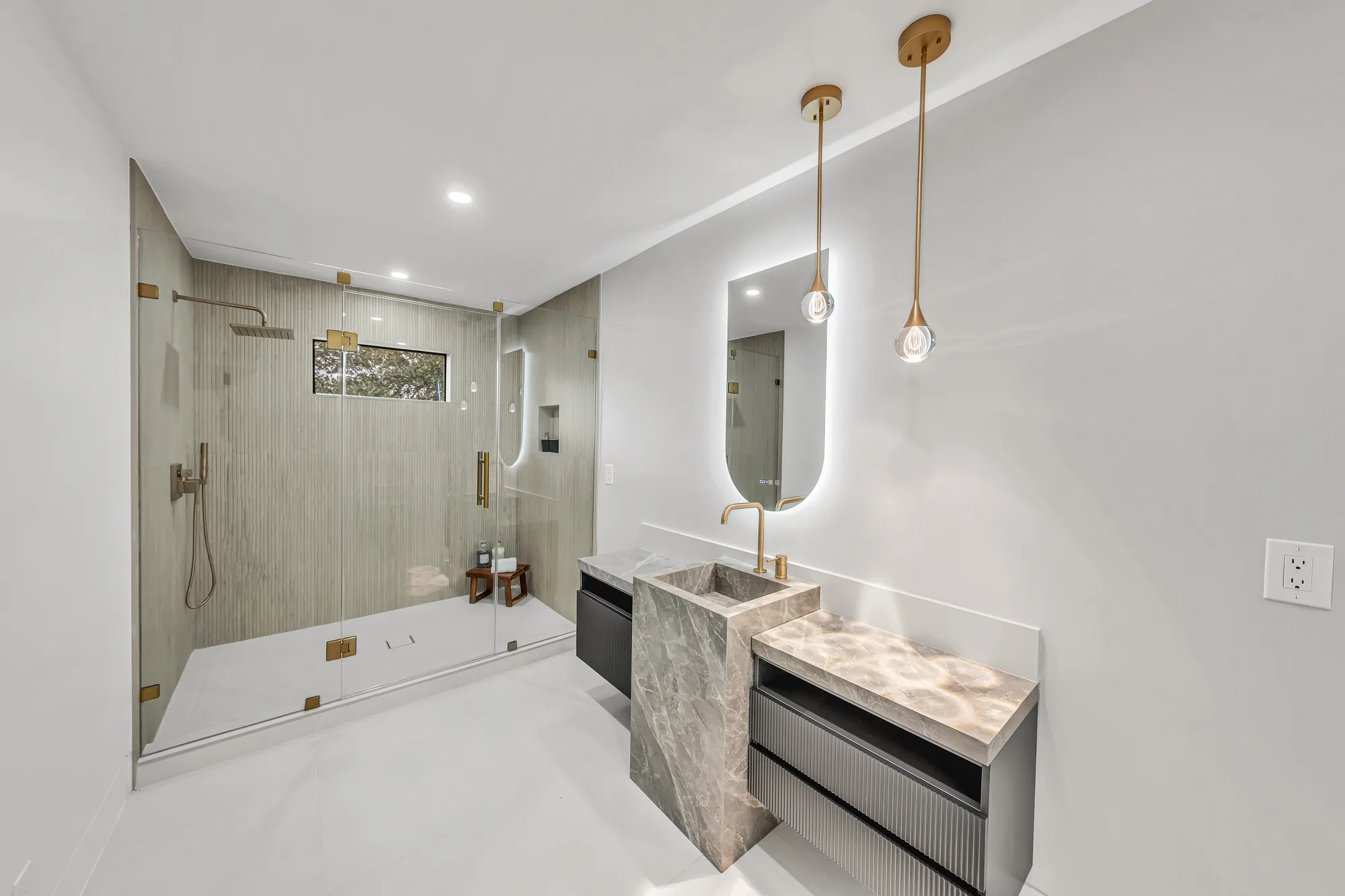Bathroom with fluted floating vanity, freestanding stone pedestal sink and walk-in glass shower.
