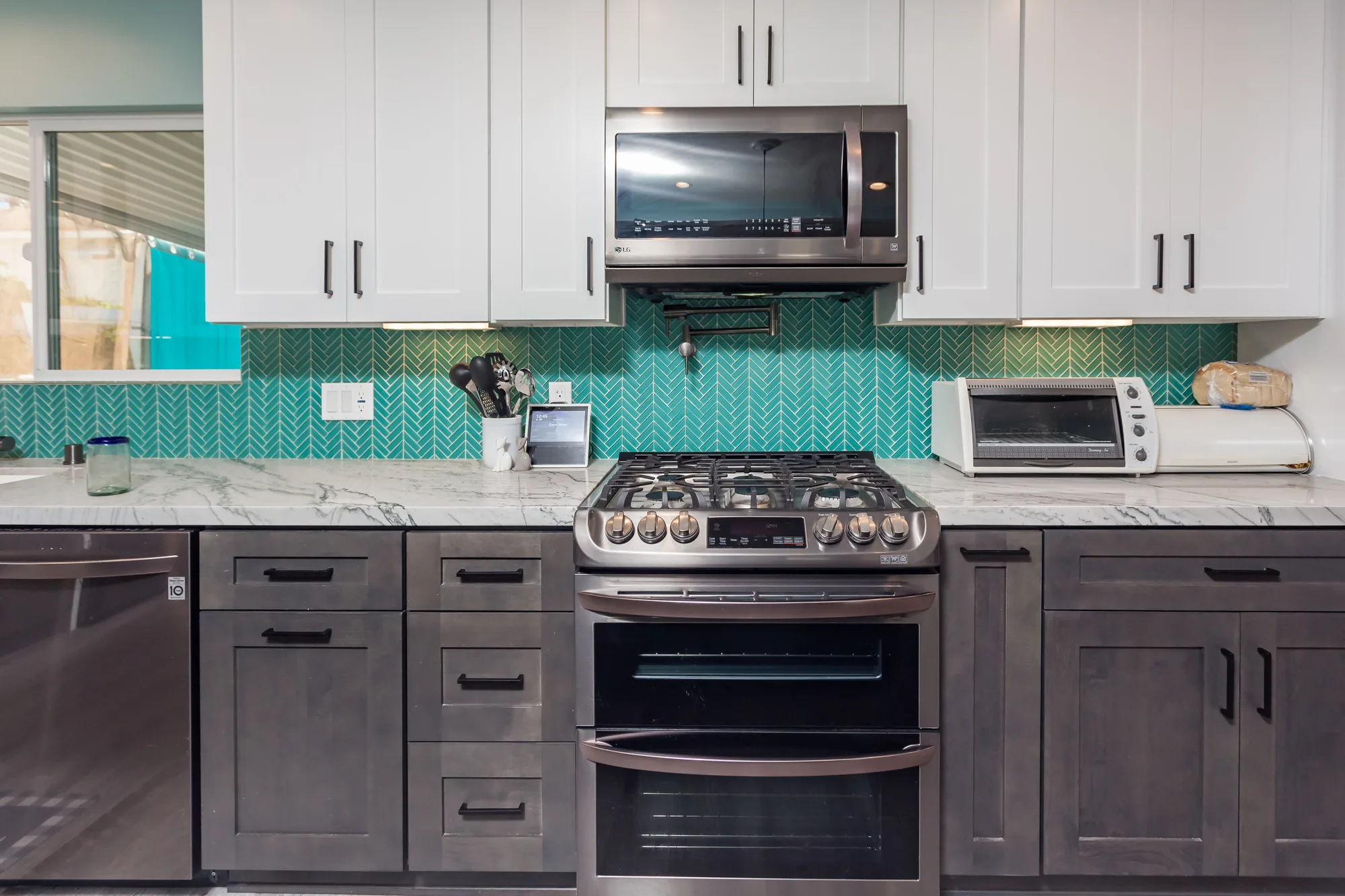 Gas range flanked by gray shaker drawer bases and white stone counters under white upper cabinets.