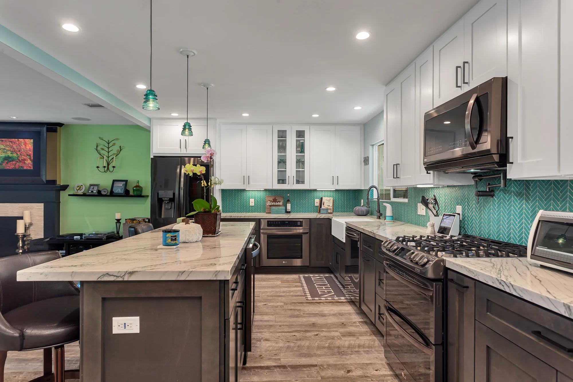 Kitchen island and cabinet run seen from the adjoining living room with a green painted accent wall.