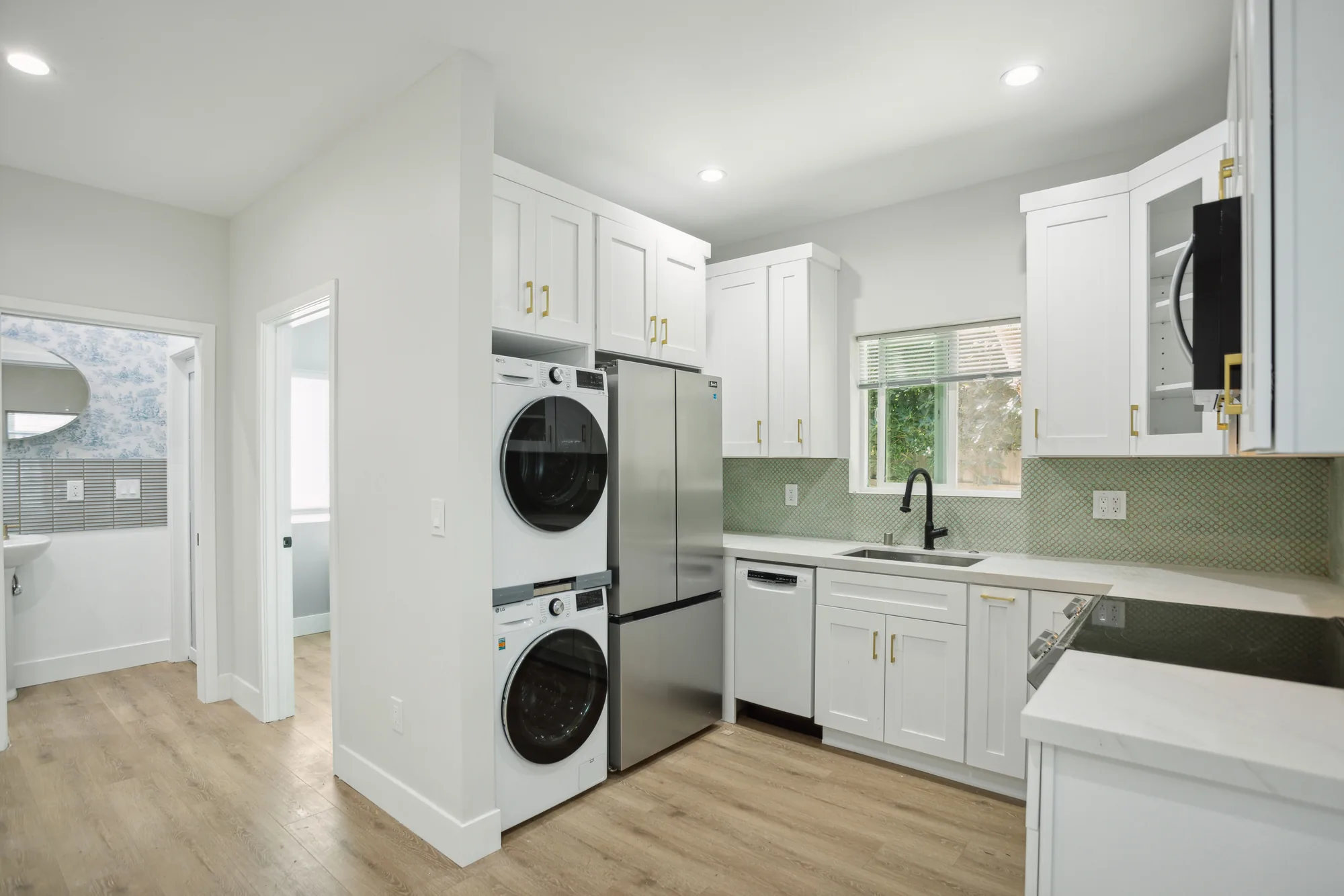 Kitchen with a stacked washer and dryer and stainless refrigerator built into a cabinet bay.