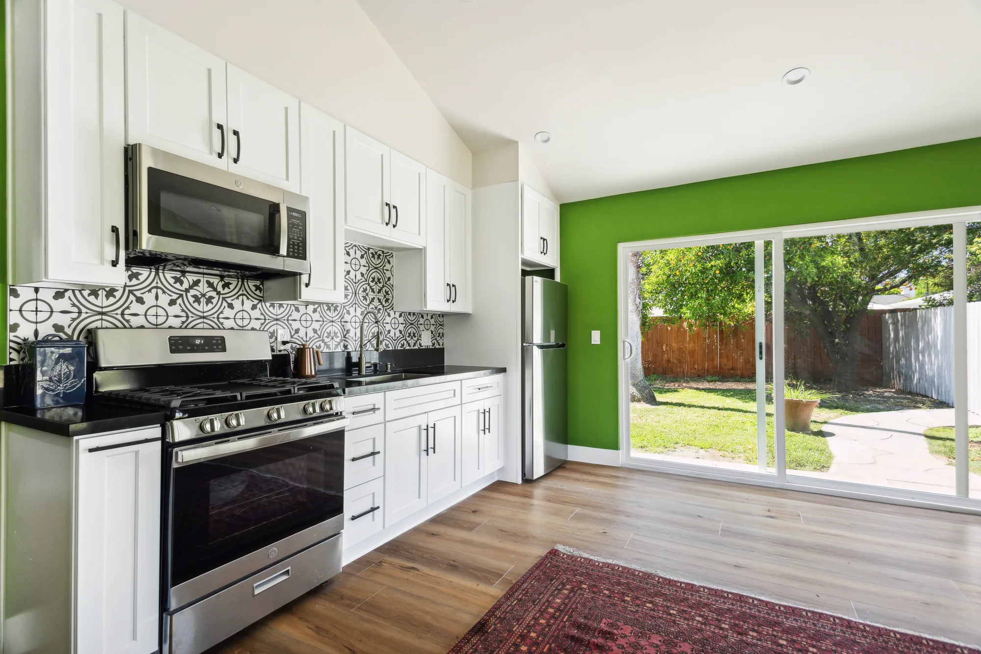 Kitchen counter and range looking toward a wide sliding glass door that opens onto a green lawn.