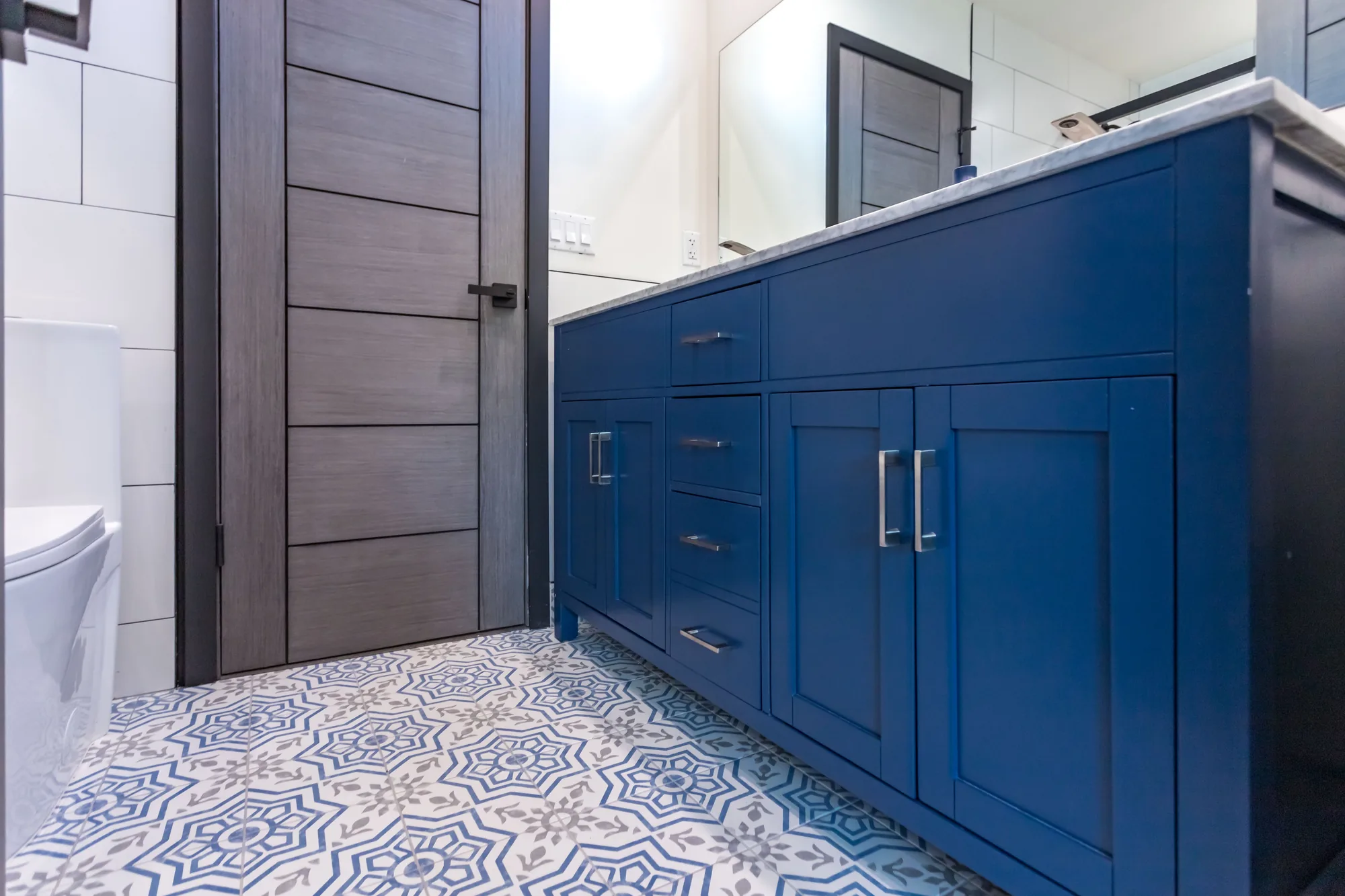 Angled view of a navy shaker vanity above blue and gray patterned floor tile.