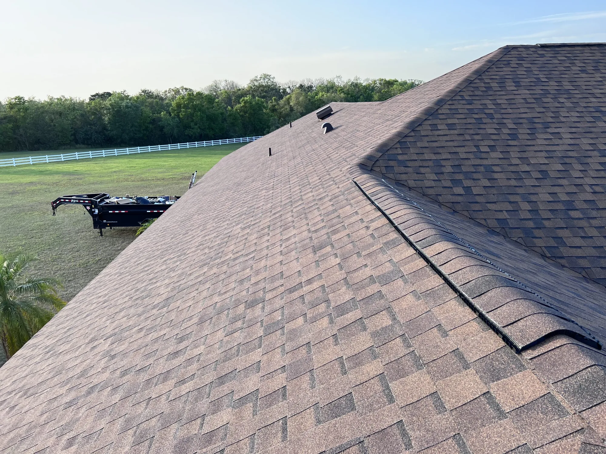 Asphalt shingle roof ridge against a clear sky