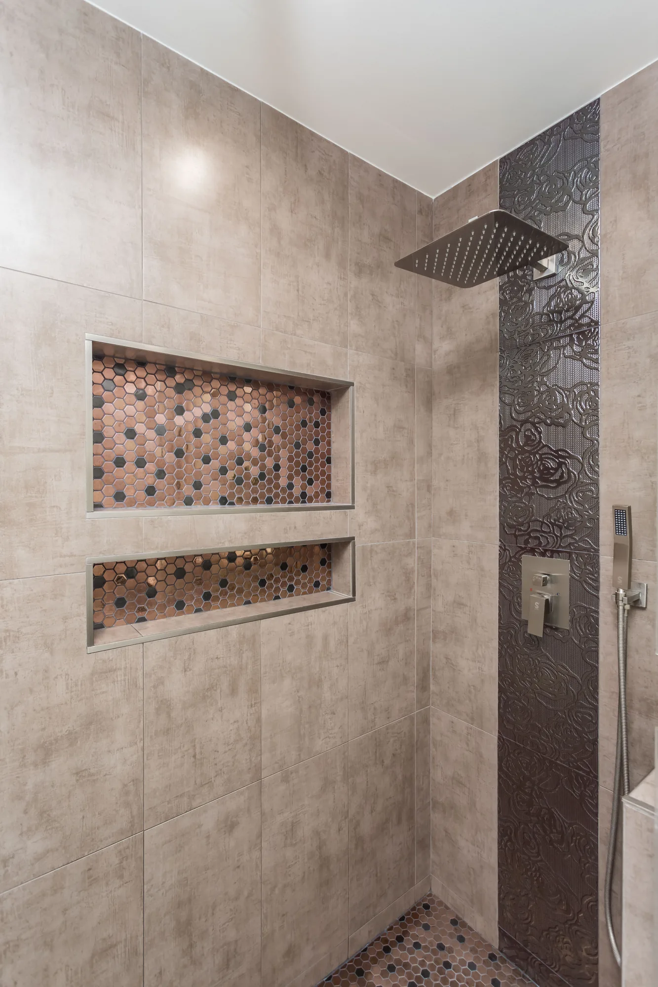 Shower interior with two tiled niches, a square rain head and a dark textured tile accent stripe.