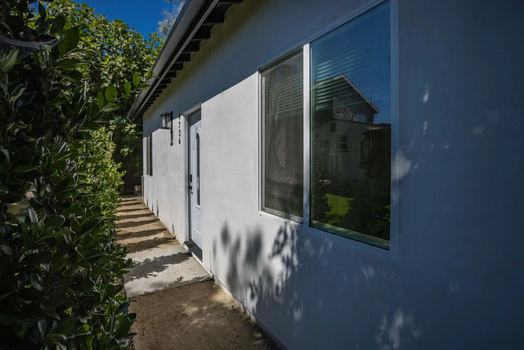 Side elevation of the stucco unit with a large picture window and a concrete walkway alongside.