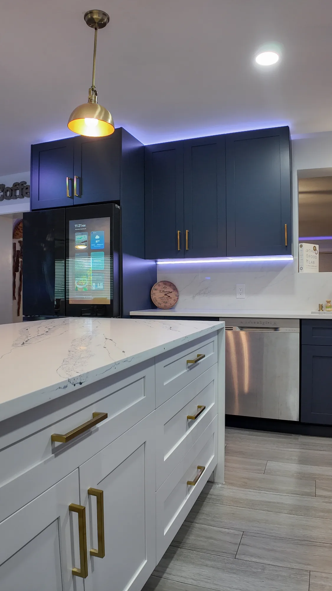 Two-tone kitchen with a white shaker island in front of navy cabinets and a stainless refrigerator.