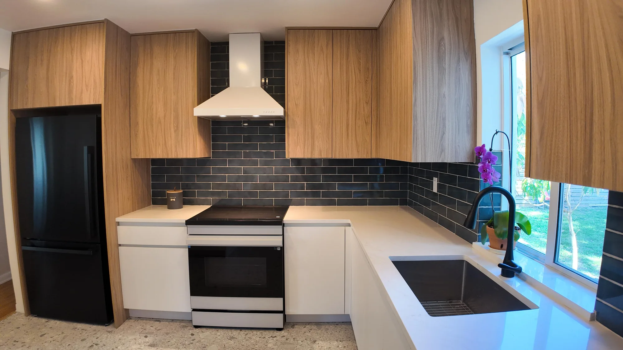 Two-tone kitchen showing a black refrigerator, white range and light countertops along an L-shaped run.