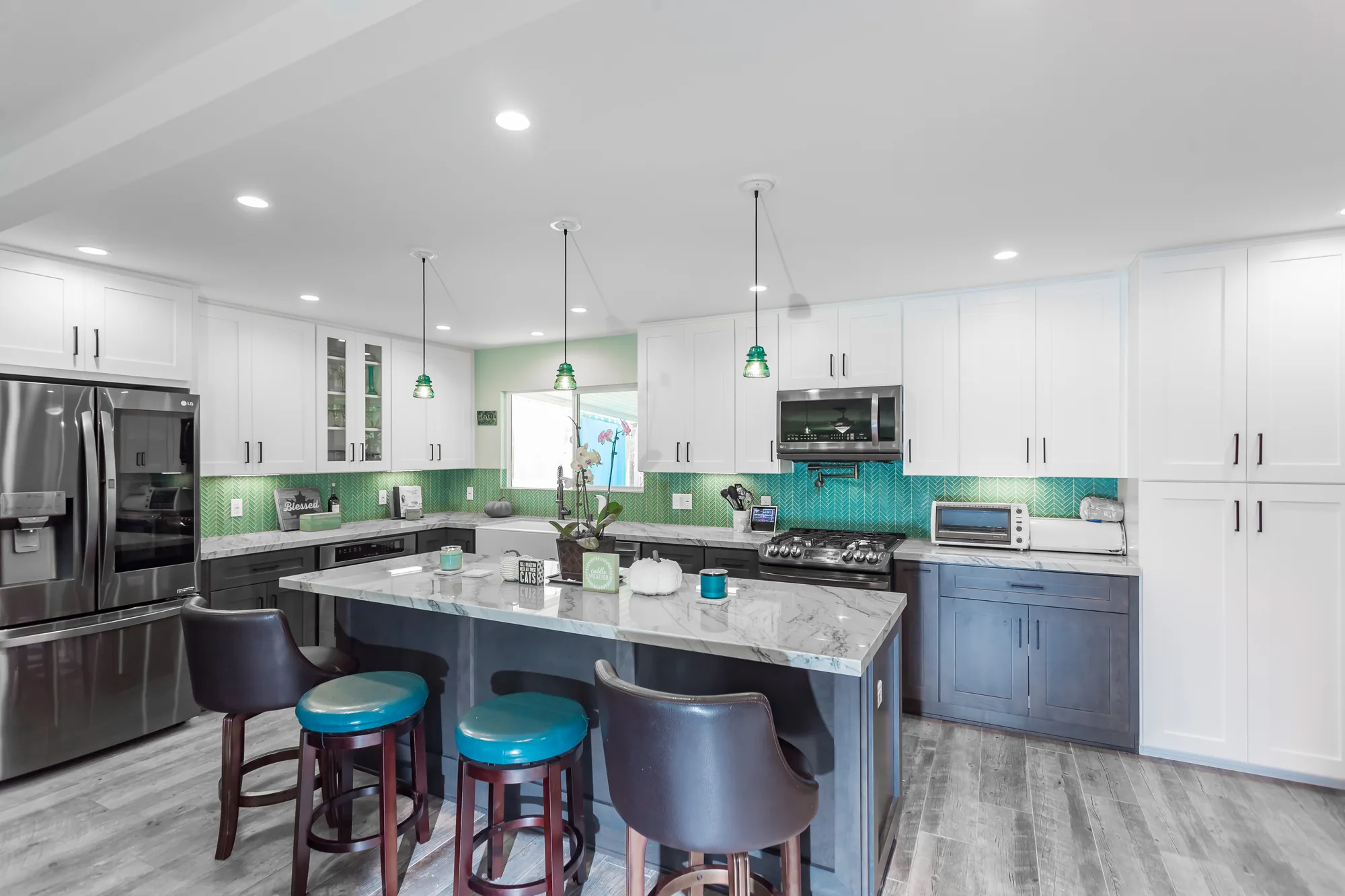 Remodeled kitchen with white and gray shaker cabinets, a marble-look island, and teal herringbone tile.