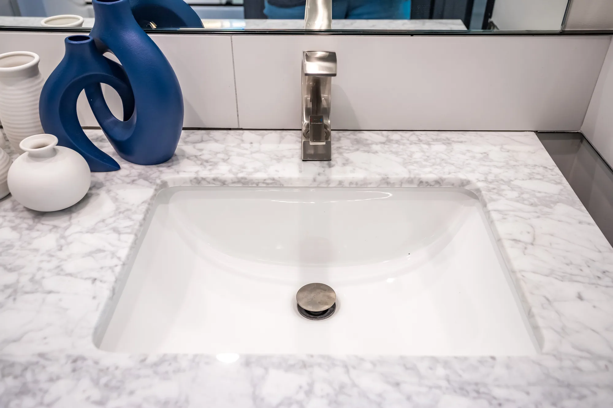 Undermount rectangular sink in a veined marble-look countertop with a brushed nickel faucet.