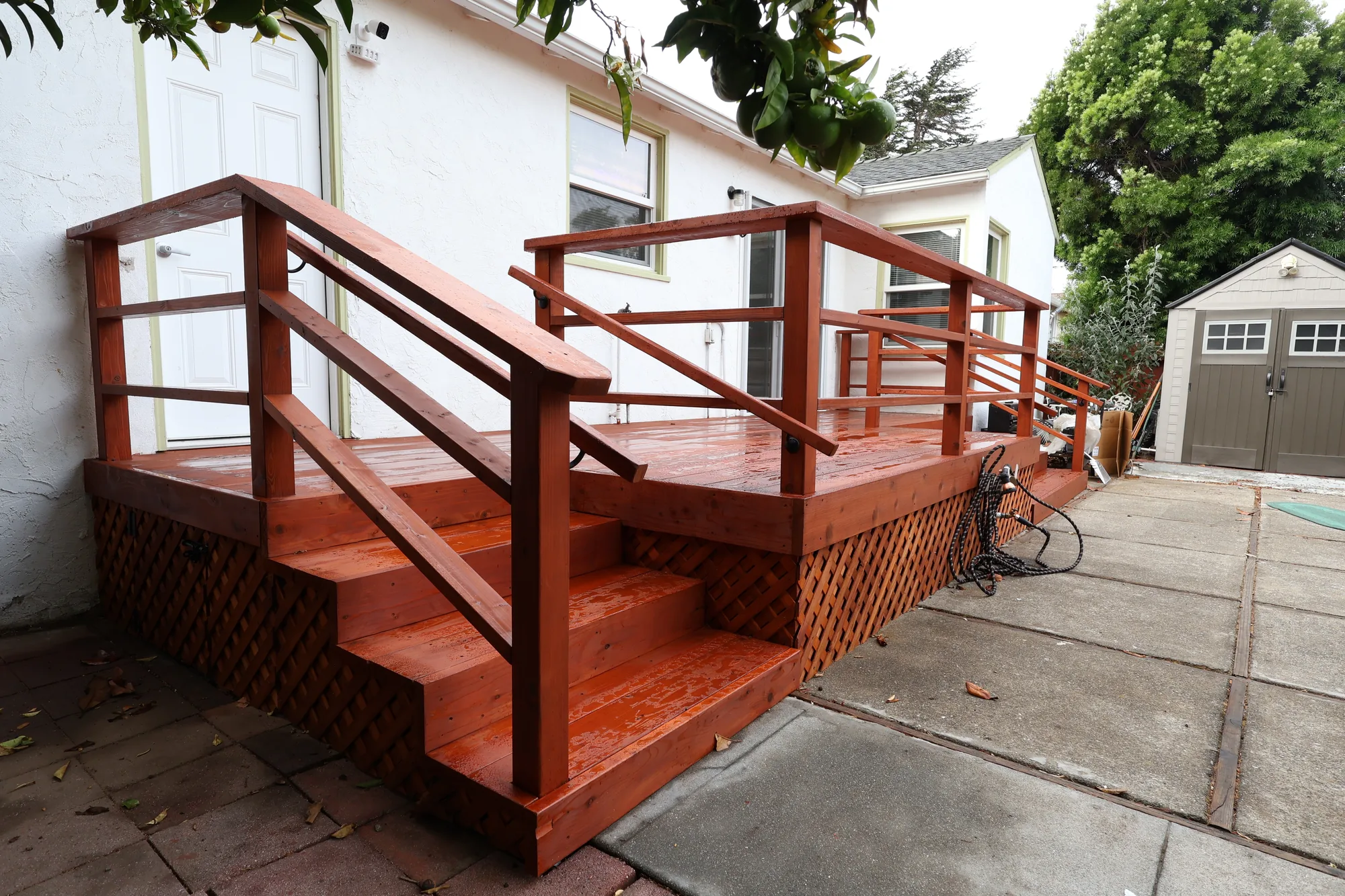Angled view of a low wood deck showing wide stairs, horizontal rail infill and diagonal lattice skirting.